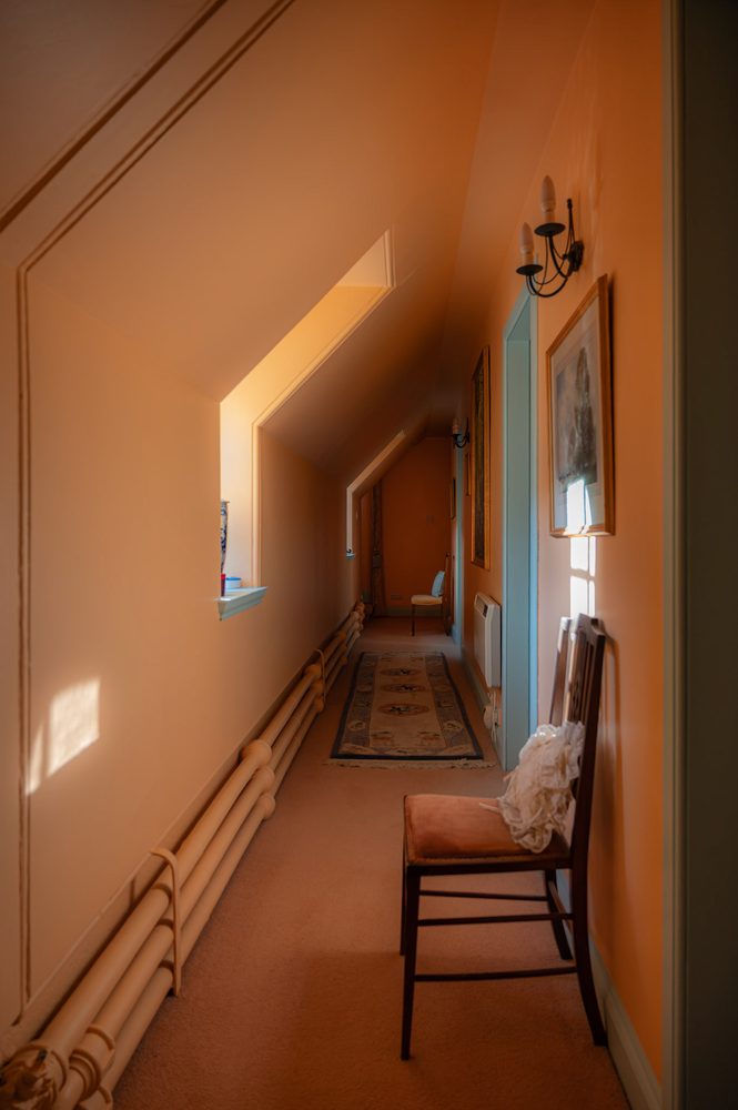 Sloped-ceiling passage with sconce and chair