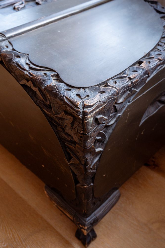 Carved corner of a dark wood chest